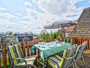 a table with chairs and an umbrella on a deck at Apartment Am Malerwinkel by Interhome in Schieder-Schwalenberg