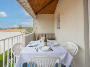 einen Tisch mit weißen Stühlen und eine Flasche Wein auf dem Balkon in der Unterkunft Apartment Les Jardins de l'Océan-42 by Interhome in Vaux-sur-Mer