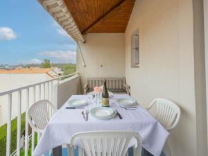 a table with white chairs and a bottle of wine on a balcony at Apartment Les Jardins de l'Océan-42 by Interhome in Vaux-sur-Mer