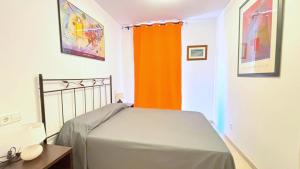 ein Schlafzimmer mit einem Bett und einem orangenen Vorhang in der Unterkunft Puigmal in Empuriabrava