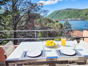 - une table avec un bol de fruits et une vue sur l'eau dans l'établissement Apartment Lago di Lugano-9 by Interhome, à Bissone