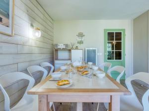 a dining room with a wooden table and white chairs at Holiday Home Domaine Golf Resort-2 by Interhome in Lacanau-Océan