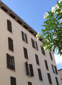 un bâtiment blanc avec des fenêtres marron et un arbre dans l'établissement Grand Hôtel De Calvi, à Calvi