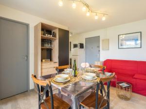 jadalnia ze stołem i czerwoną kanapą w obiekcie Apartment Les Balcons de l'Atlantique-12 by Interhome w mieście Pontaillac