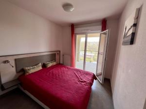 um quarto com uma cama vermelha e uma janela em San José em Juvignac