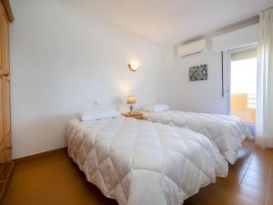 dwa łóżka w pokoju z białymi ścianami w obiekcie Apartment Voramar-5 by Interhome w mieście Calpe