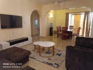 a living room with a table and a tv at Elegant furnished rooms with swimming pool in Nyali in Mombasa