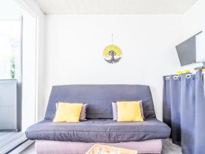 a blue couch in a living room with yellow pillows at Studio Port Arcachon-2 by Interhome in Arcachon
