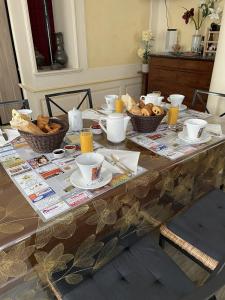 une table avec des tasses et des bols de nourriture dans l'établissement Maison Galland, à Lapalisse