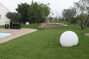 a white ball sitting in the grass next to a pool at la villa d'Ariane-piscine-jaccuzi-15 mn Mer in Vendargues +28 photos