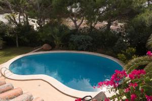 - une piscine dans une cour ornée de fleurs roses dans l'établissement Top Rated Menorca Villa, Binibecca, à Binibeca