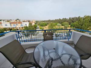 a glass table and chairs on a balcony at Iris Village in Paphos