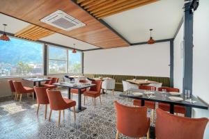 Levelup Plus Pinaaki Inn في ريشيكيش: مطعم بطاولات وكراسي ونوافذ كبيرة