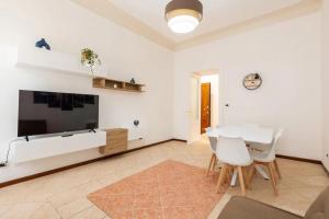 a white living room with a table and a tv at [San Giusto's Clock] Storico Appartamento in Trieste +11 photos