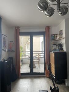 sala de estar con puerta corredera de cristal y balcón en Chambre suite privée à Boulogne, en Boulogne-Billancourt
