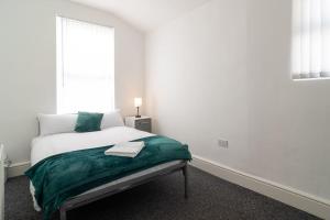 a white bedroom with a bed and a window at 4 bed house parking Wi-Fi garden in Wallasey