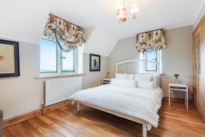 - une chambre avec un lit blanc et 2 fenêtres dans l'établissement Laverton Hill Farm, Snowshill, for up to 16, à Broadway