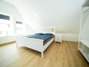 een witte slaapkamer met een wit bed en een houten vloer bij Holiday Home Mia by Interhome in Lügde