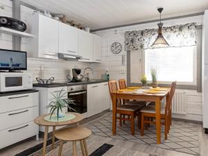 uma cozinha com armários brancos e uma mesa e cadeiras em Holiday Home Riekko by Interhome em Enontekiö