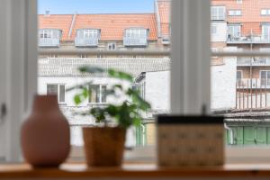 a plant sitting on a window sill with a view of a building at Come Stay - 2BR Det perfekte hjem for 5 in Aalborg
