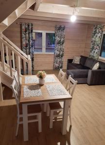 a dining table and chairs in a living room at Mazury - domki Wzgórza Dybowskie całoroczne- bania z jacuzzi , sauna in Dybowo