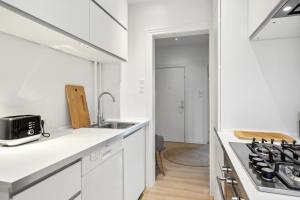 a white kitchen with a sink and a stove at Come Stay - 2BR Det perfekte hjem for 5 in Aalborg