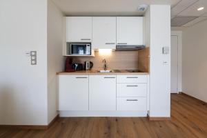 a kitchen with white cabinets and a sink at OVELIA Aix-les-bains - Le Pavillon Victoria in Aix-les-Bains