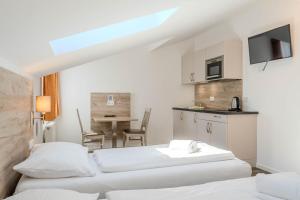 a room with two beds and a kitchen with a table at Aparthotel Oberfeld West München in Straßlach-Dingharting