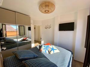Schlafzimmer mit einem Bett mit einem Spiegel und einem TV in der Unterkunft Coeursanary in Sanary-sur-Mer
