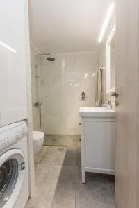 a white bathroom with a sink and a washing machine at Varkiza Seaside 2BD Apartment in Varkiza