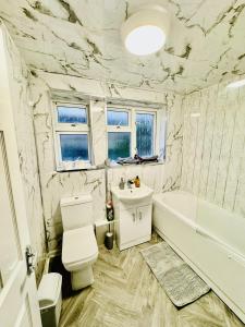 a white bathroom with a toilet and a tub and a sink at 4-Bed Full House Stourbridge Birmingham in Stourbridge