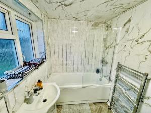 baño con bañera blanca, lavamanos y tubermott en 4-Bed Full House Stourbridge Birmingham en Stourbridge
