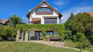 ein Haus mit einem Balkon und einer Bank in der Unterkunft Panorama Apartment in Tihany