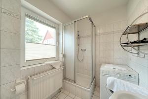 a white bathroom with a shower and a sink at Luv in Zingst