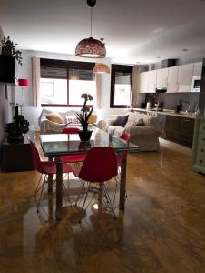 a living room with a glass table and red chairs at Moderno y Amplio apartamento Valdeolleros SRosa in Córdoba