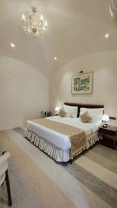 Un dormitorio con una cama grande y una lámpara de araña. en Ayodhya haat Luxury Cottages, en Ayodhya