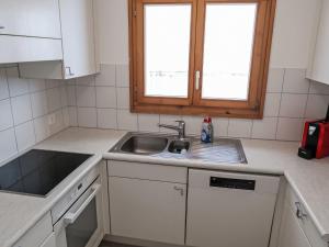 a kitchen with white cabinets and a sink and two windows at Apartment Utoring Acletta-2 by Interhome in Disentis