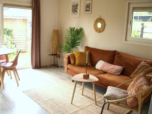 - un salon avec un canapé brun et une table dans l'établissement Gezellig gemoderniseerd chalet op de Veluwe, à Putten