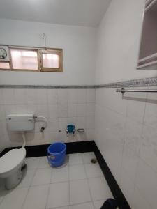 a bathroom with a toilet and a blue bucket at Home Away From Home Cute 3 bedroom House G floor in Srinagar