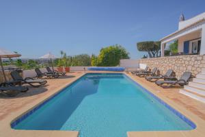 a swimming pool with chairs and a house at Casa Montaza 4 Bedroom Villa with private pool in Lagos in Lagos