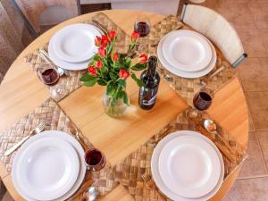 une table avec des assiettes blanches et des fleurs rouges dans un vase dans l'établissement Holiday Home Dubrove by Interhome, à Pražnice