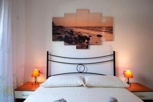 um quarto com uma cama com 2 candeeiros e uma fotografia em Villetta con giardino a 500 mt dalla spiaggia em Marongiu