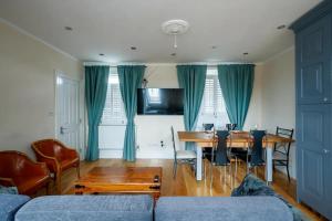 ein Wohnzimmer mit einem Esstisch und blauen Vorhängen in der Unterkunft Immaculate 4-Bed House in London in London