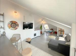 uma sala de estar com um sofá e um relógio na parede em Mansarda Vista Mare a Zinola em Savona