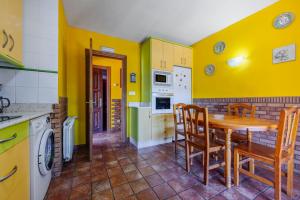 a kitchen with yellow walls and a wooden table and chairs at Posada Paraso Iris in Isla