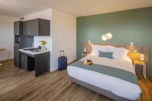 a bedroom with a large bed and a kitchen at All Suites Appart Hôtel - Le Havre Centre - Les docks in Le Havre
