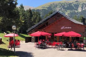 een restaurant met rode tafels en stoelen en rode parasols bij Apartament Pla del Roc in La Molina