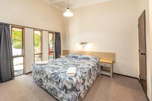 a bedroom with a bed and a table and a window at Riverside Motel in Whanganui