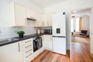 uma cozinha com armários brancos e um frigorífico branco em St Marks House, Easton, Great Location, Free Parking em Bristol