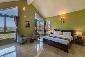 a bedroom with a large bed and large windows at SaffronStays Caramelo - a private swimming pool villa nestled amidst beautiful landscaping and gardens in Lavasa in Lavasa